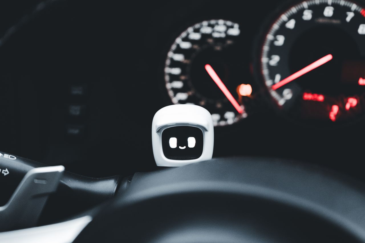 project-02-b Futuristic smiling robot gadget on a car dashboard symbolizing modern technology and innovation.